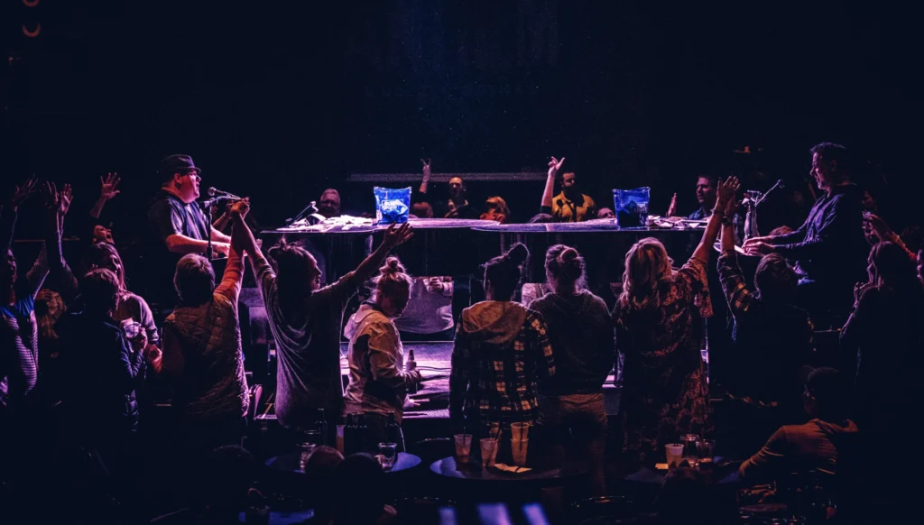 Two men playing piano on stage in front of happy crowd