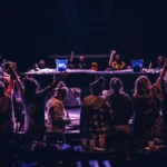 Two men playing piano on stage in front of happy crowd